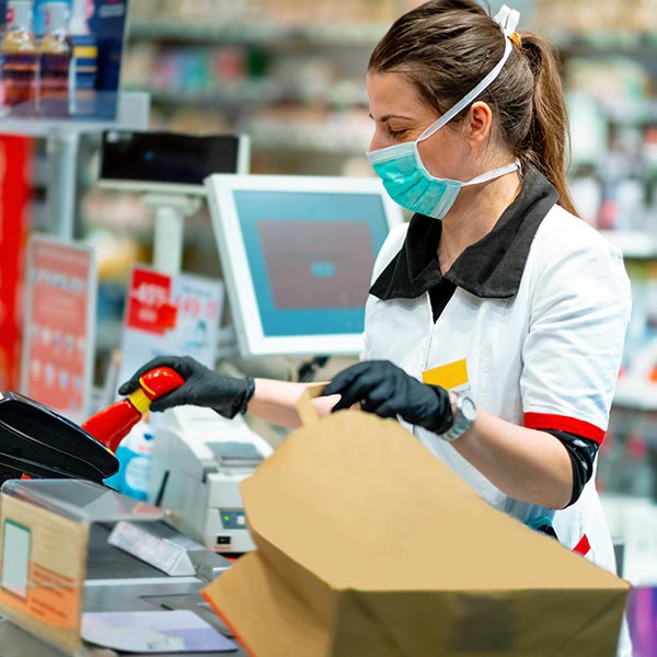 Woman cashier in mask and gloves working at the register